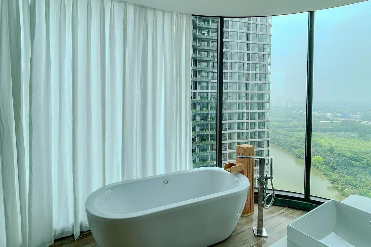 Un baño moderno con una bañera independiente, un ventanal con vistas a la ciudad y suelo de madera.