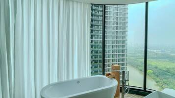 Ein modernes Badezimmer mit einer freistehenden Badewanne, einem großen Fenster mit Blick auf die Stadt und einem Holzboden.