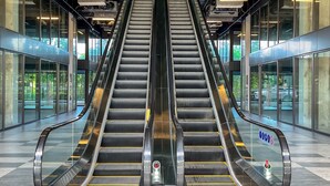 An indoor escalator in a modern building with glass walls and metal railings. - Onsen Landmark Luxury Apartments (Phung Cong)