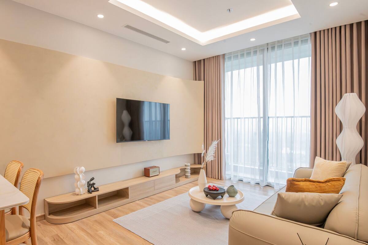 Una sala de estar moderna con un televisor de pantalla plana, un sofá, una mesa de centro y un comedor con sillas.