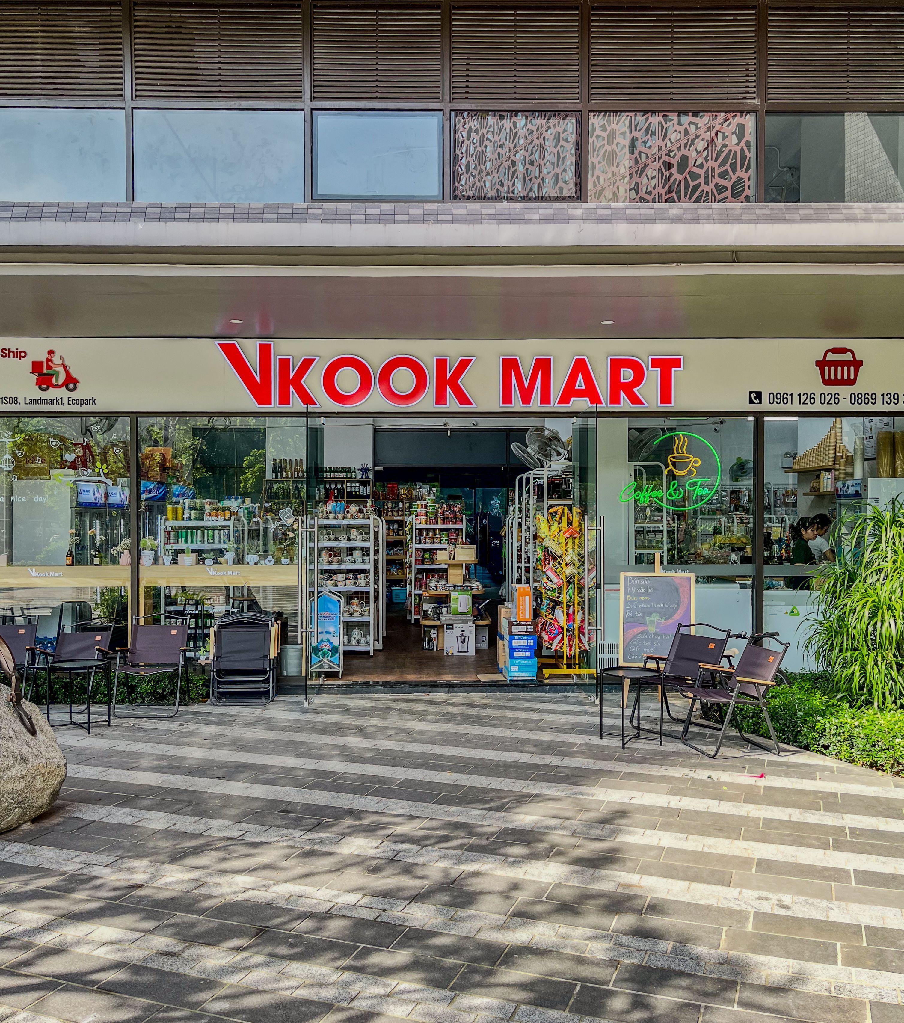 De buitenkant van een NkooK Mart met een duidelijke ingang, een terras en een verscheidenheid aan zichtbare producten.