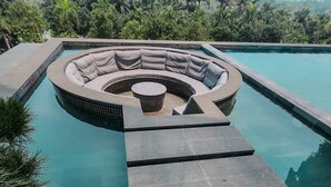 A modern pool area with a circular seating area and a tiered stone pathway leading to the water. - Onsen Landmark Luxury Apartments (Phung Cong)