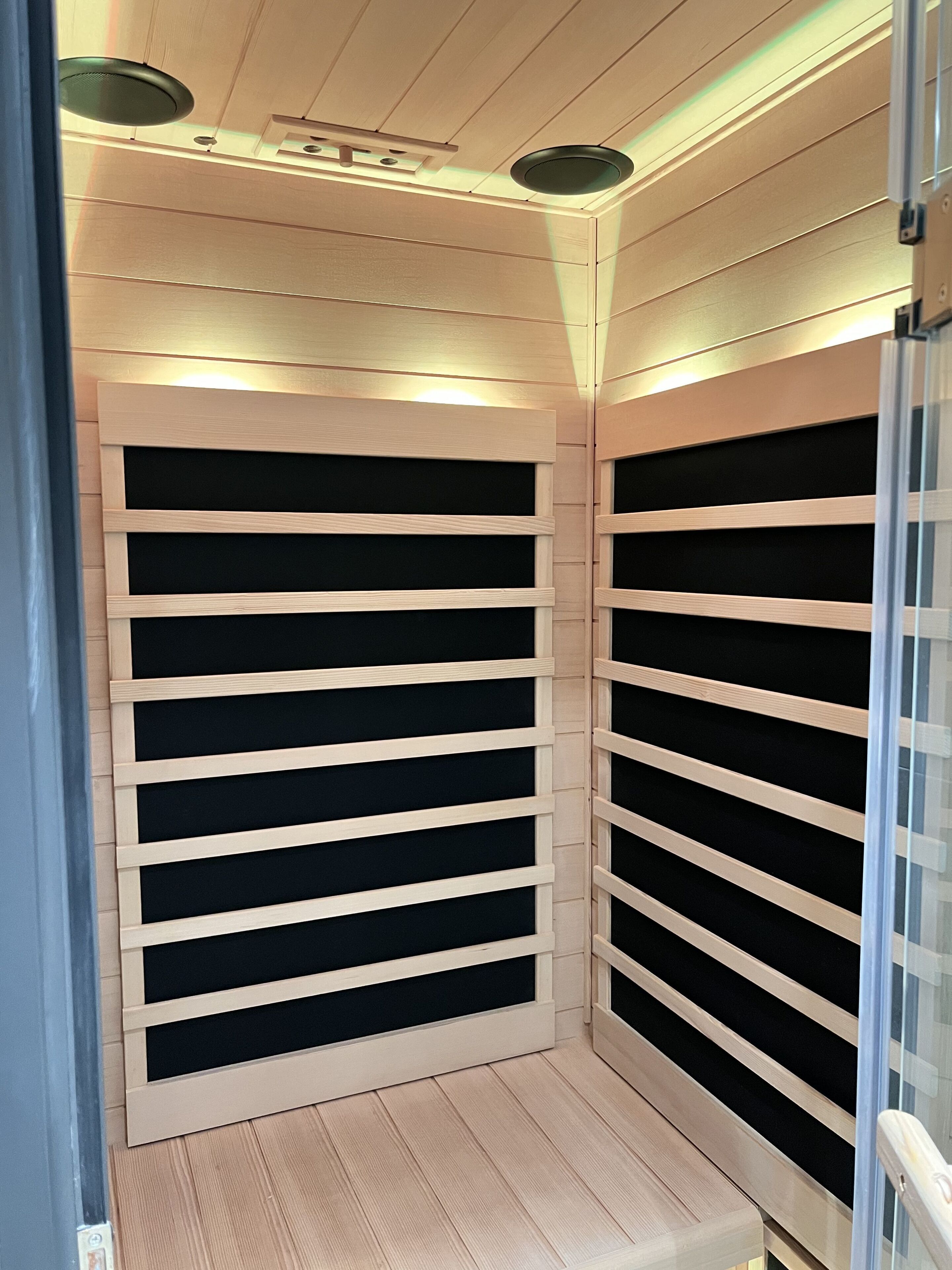 Een hoek van een kamer met houten lambrisering en een zwart wandrek.