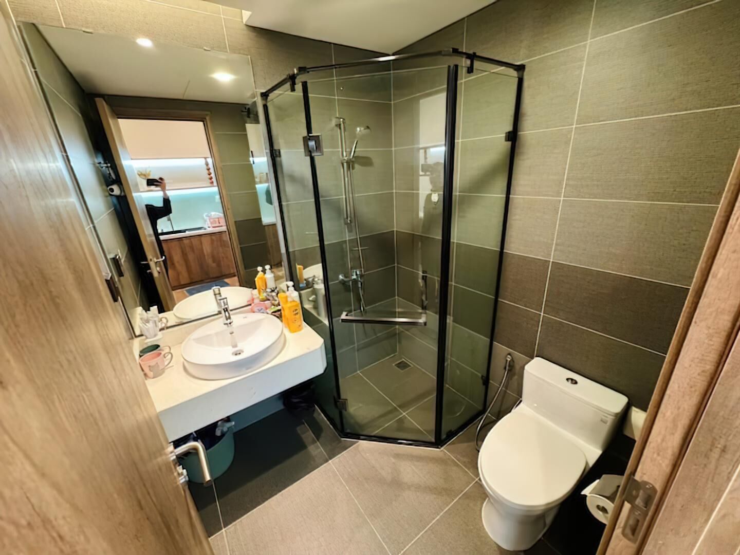 A modern bathroom with a glass-enclosed shower, a white sink, and a toilet.