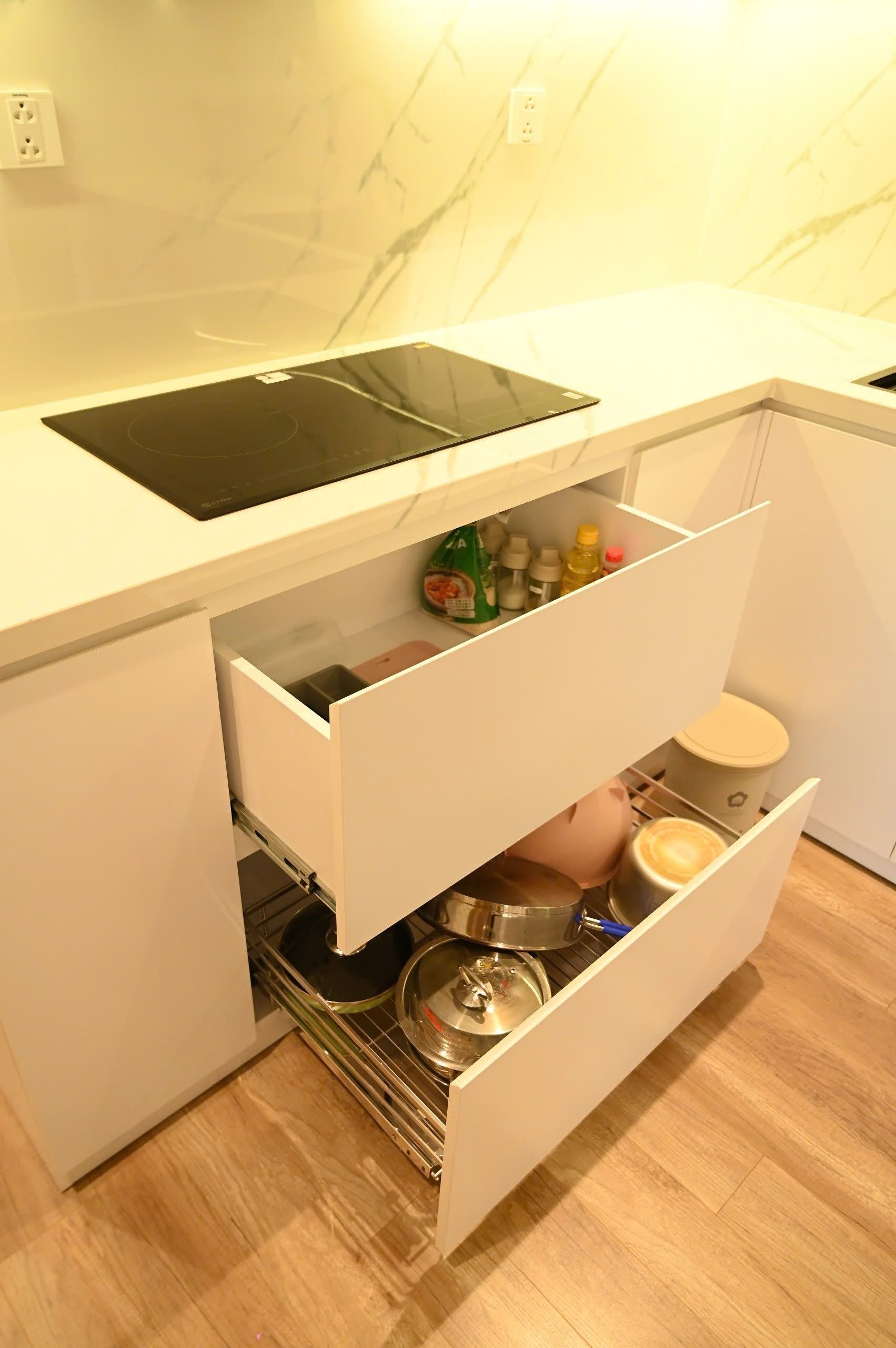 A kitchen with a built-in induction cooktop, white cabinetry, and a stainless steel sink.