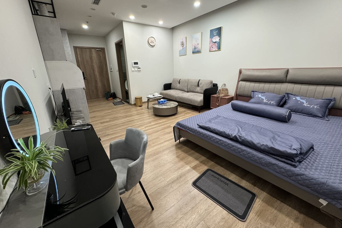 Un dormitorio moderno con una cama grande, un escritorio, un sofá y una mesa de comedor.