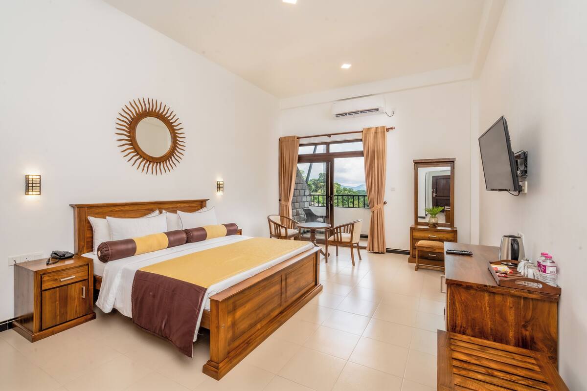 Une chambre d’hôtel avec un grand lit, un bureau, une chaise, une télévision et une fenêtre avec des rideaux.