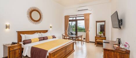 A hotel room with a large bed, a desk, a chair, a TV, and a window with curtains.