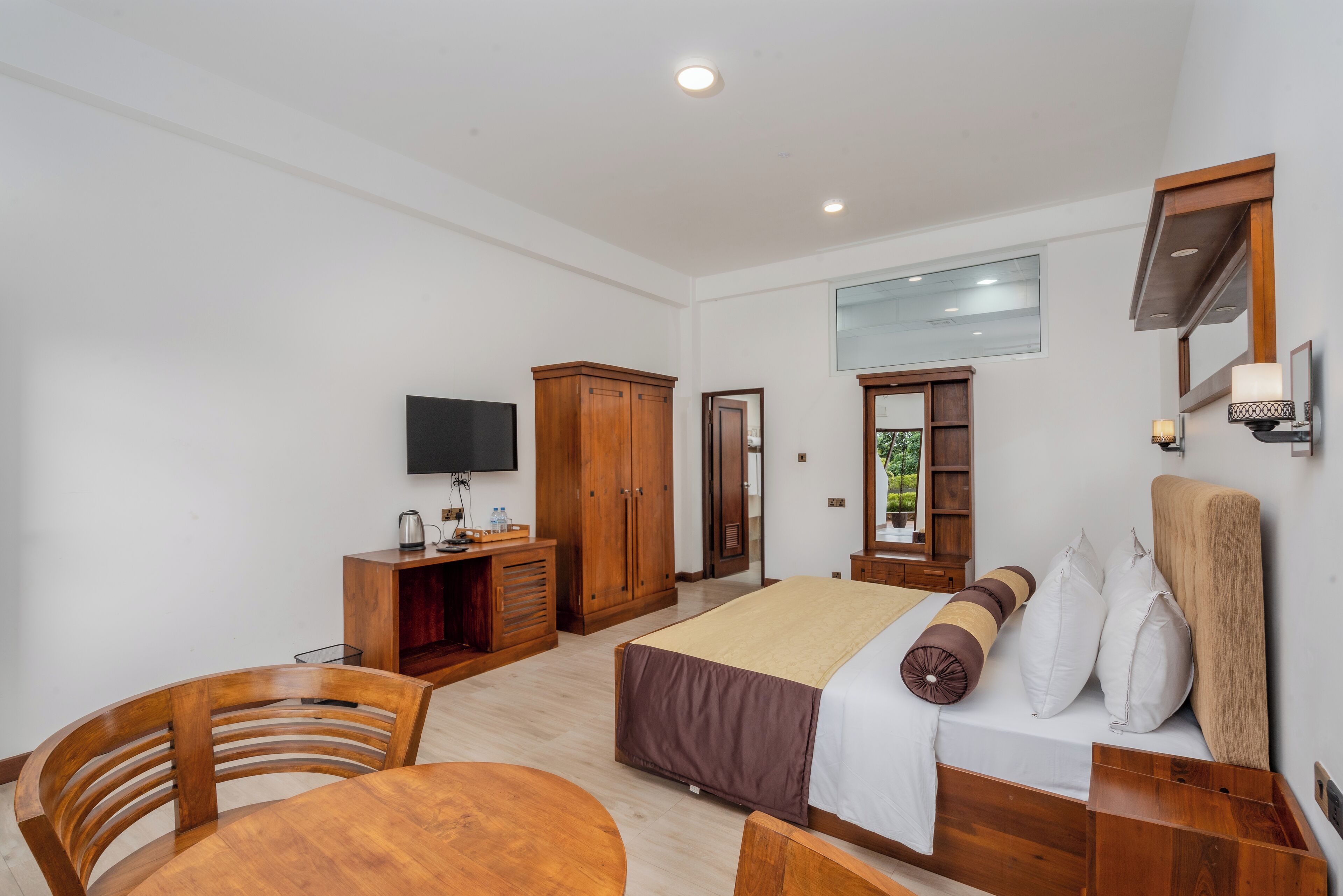 A hotel room with a bed, wooden furniture, a TV, and a window.