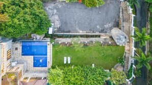 Vue aérienne d’un quartier résidentiel avec une piscine, un petit jardin et une allée pavée.