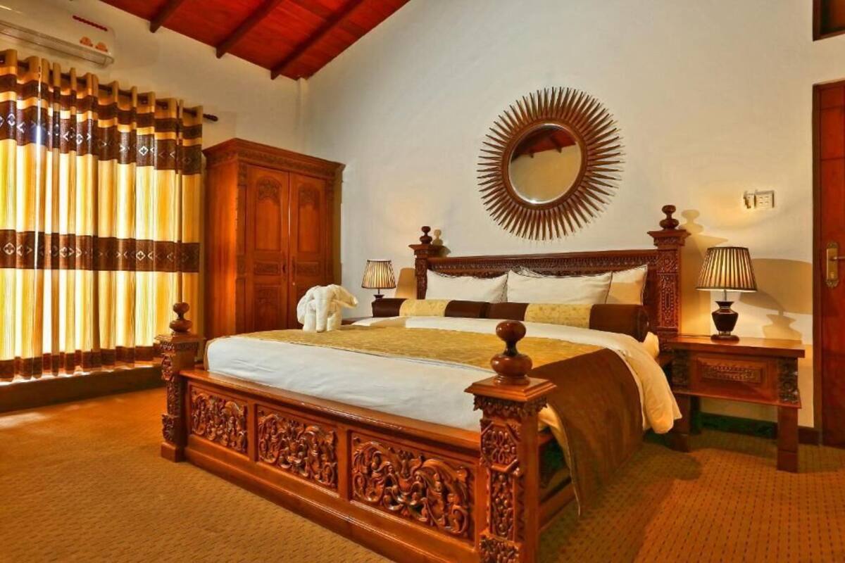 Une chambre à coucher avec un grand lit, une tête de lit en bois, un miroir et une armoire.