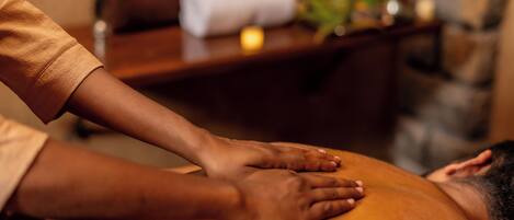 A massage therapy session in progress with a focus on the hands of the therapist and the back of the client.