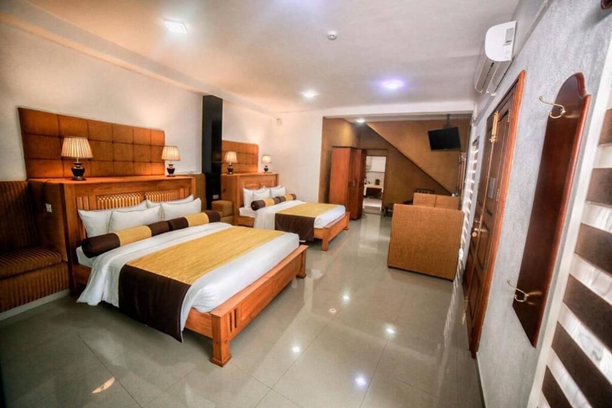 Une chambre d’hôtel avec deux lits, un canapé, une télévision et un escalier menant à l’étage supérieur.