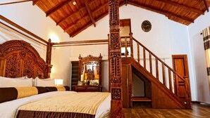 Un lit à baldaquin avec une tête de lit en bois, un escalier avec des rampes en bois et un grand miroir au mur.