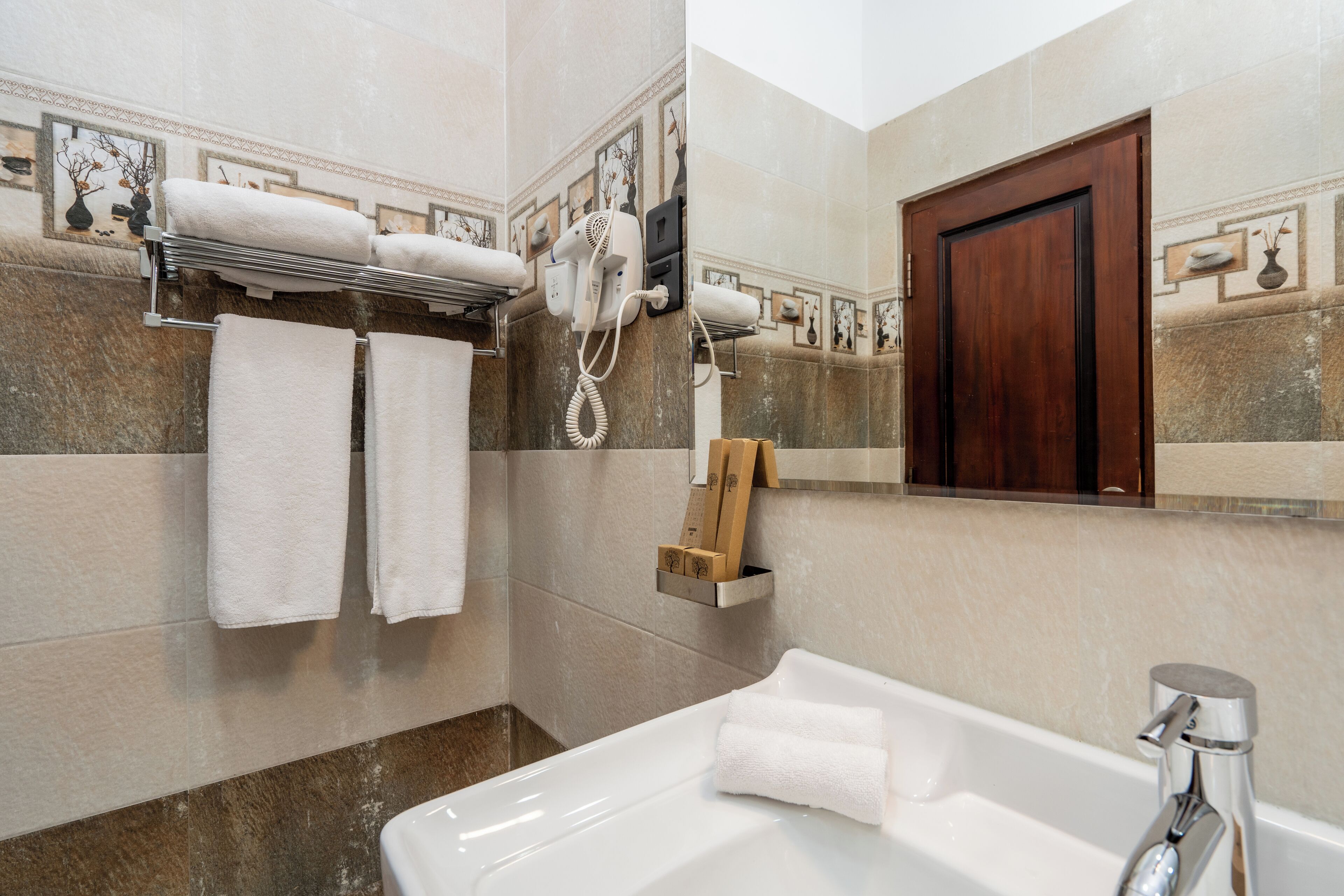 A bathroom with a bathtub, a towel rack with towels, a hairdryer, and a wooden box.