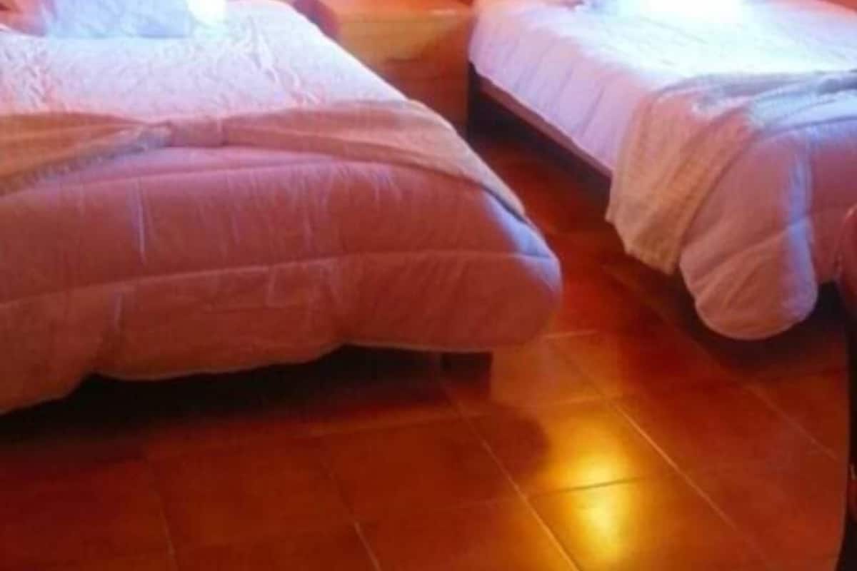 Ein Zimmer mit zwei Betten, jeweils mit Kopfteil und Kissen, und einem Bild an der Wand.