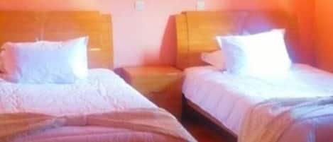 A room with two beds, each with a headboard and pillows, and a painting on the wall.