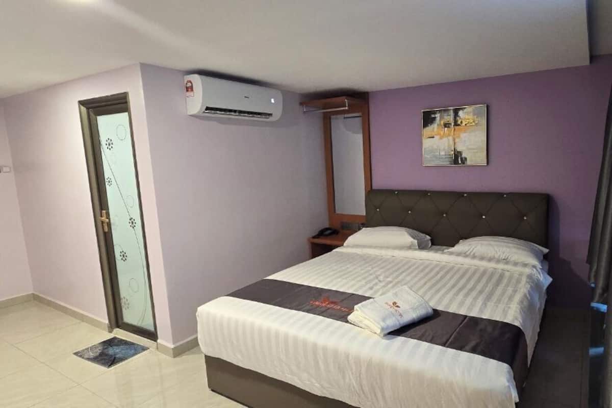 Ein Hotelzimmer mit einem Bett, einem Nachttisch, einem Spiegel, einer Klimaanlage und einer Tür mit Glasfenster.