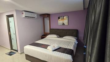 A hotel room with a bed, a nightstand, a mirror, an air conditioner, and a door with a glass panel.