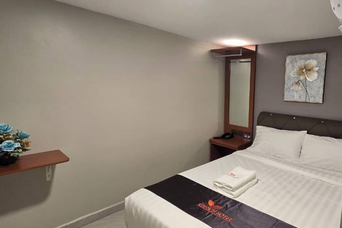 Ein Hotelzimmer mit Bett, Nachttisch, Spiegel und einem an der Wand hängenden Kunstwerk.