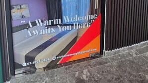 A hotel entrance with a glass door, a welcome sign, and a contact number. - Enrich Hotel Semenyih by uBook (Semenyih)