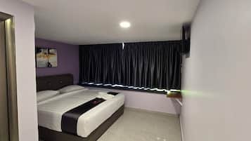 A bedroom with a bed, a window with curtains, a wall-mounted TV, and a door with a glass panel.