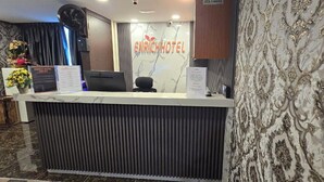A hotel reception desk with a modern design, a sign reading "ENRICH HOTEL," and a wall with ornate patterns. - Enrich Hotel Semenyih by uBook (Semenyih)
