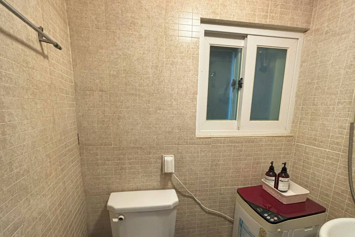Un baño pequeño con inodoro, lavadora y ventana.