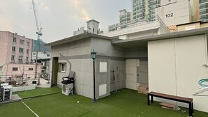 A rooftop terrace with artificial grass, a bench, and a portable toilet. - Sunrise Inn (Seoul)