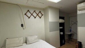 A hotel room with a large bed, a wall-mounted telephone, and a ceiling light fixture. - Sunrise Inn (Seoul)