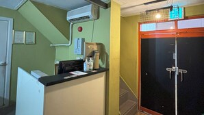 A small, enclosed room with a kitchenette, a door with a metal handle, and a ceiling with a light fixture. - Sunrise Inn (Seoul)
