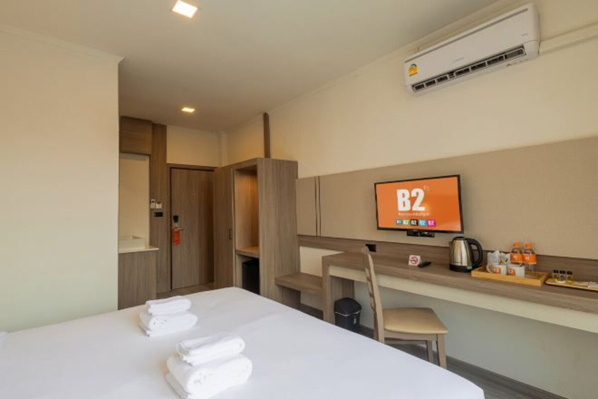 A hotel room with a bed, a desk, a chair, a TV, and a minibar.