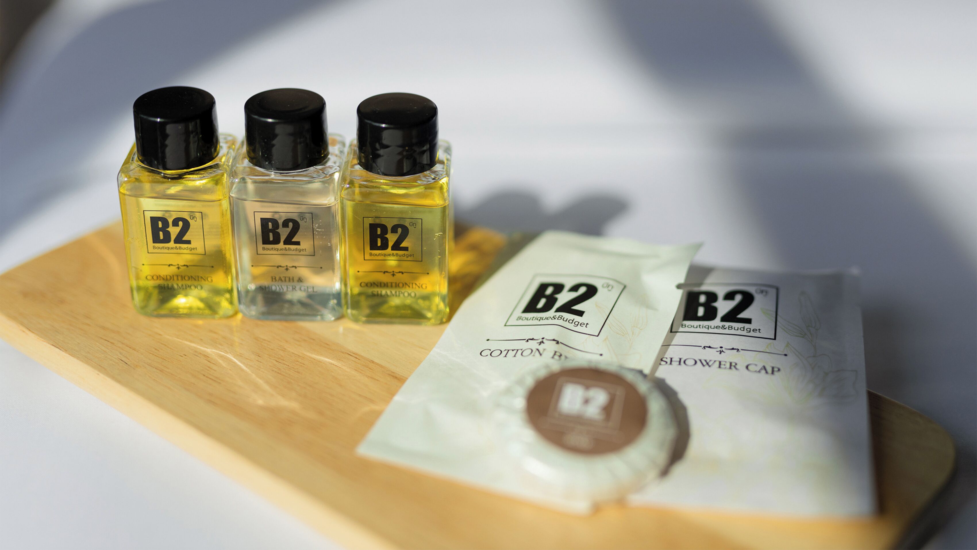 Tre flasker B2 conditioner shampoo, en flaske B2 shower gel og to B2 vatpinde med en brusehuvedæksel.