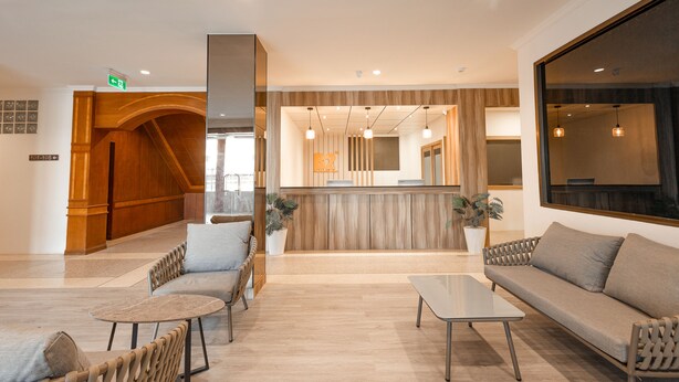 Un moderno vestíbulo de hotel con mostrador de recepción, zona de estar y un gran ventanal.