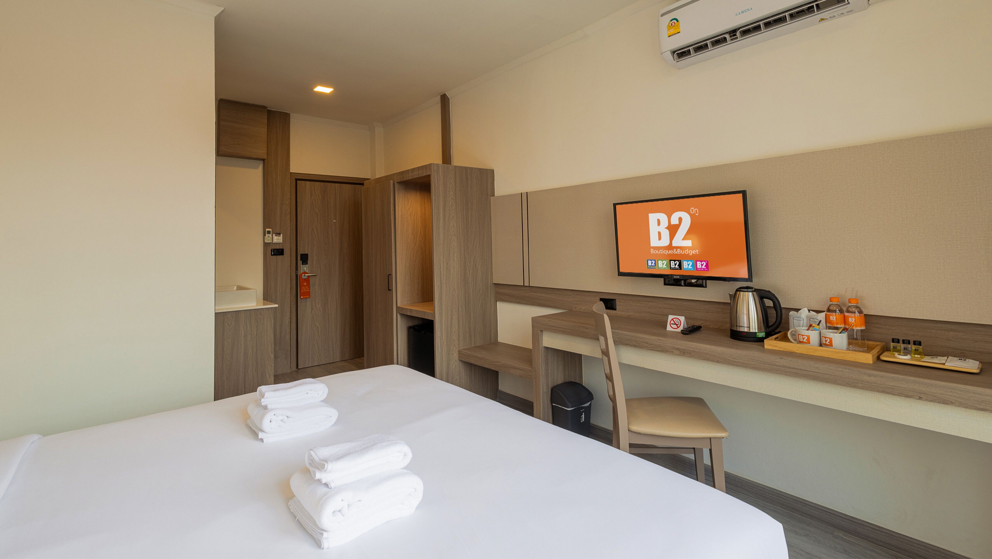 Una habitación de hotel con una cama, un escritorio, una silla, un televisor y un minibar.
