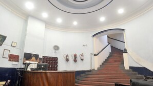 A lobby with a spiral staircase, a reception desk, and fire extinguishers on the wall. - HOTEL RAUNAK (Kolkata)