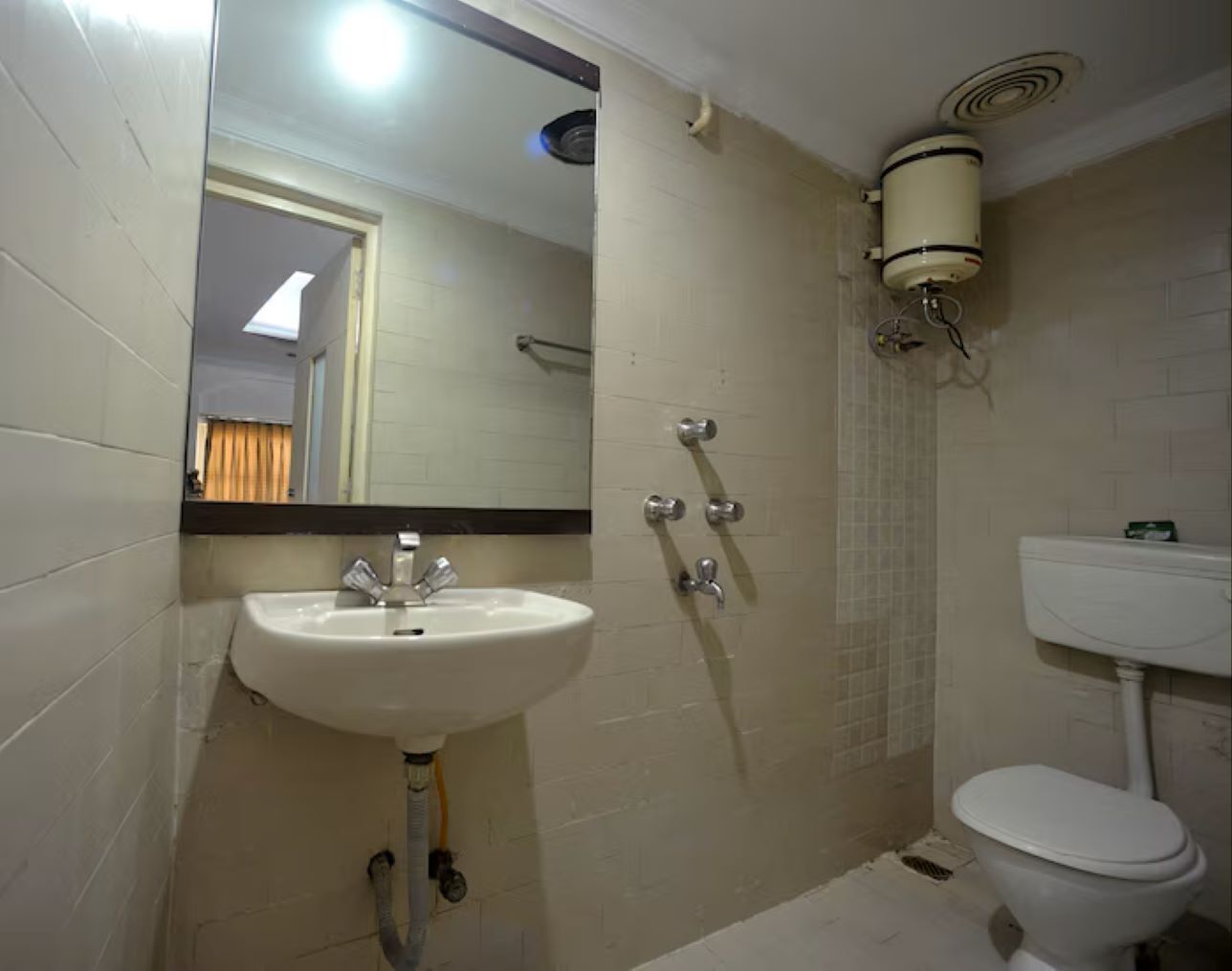 A bathroom with a sink, mirror, shower, and toilet.