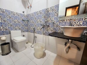 Een badkamer met toilet, douche, wastafel en betegelde wanden.