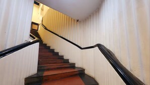 A staircase with alternating red and black steps, white walls, and a black handrail. - HOTEL RAUNAK (Kolkata)