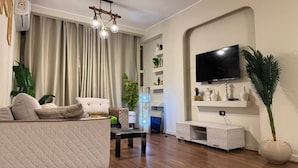A modern living room with a sofa, coffee table, TV, and decorative plants.