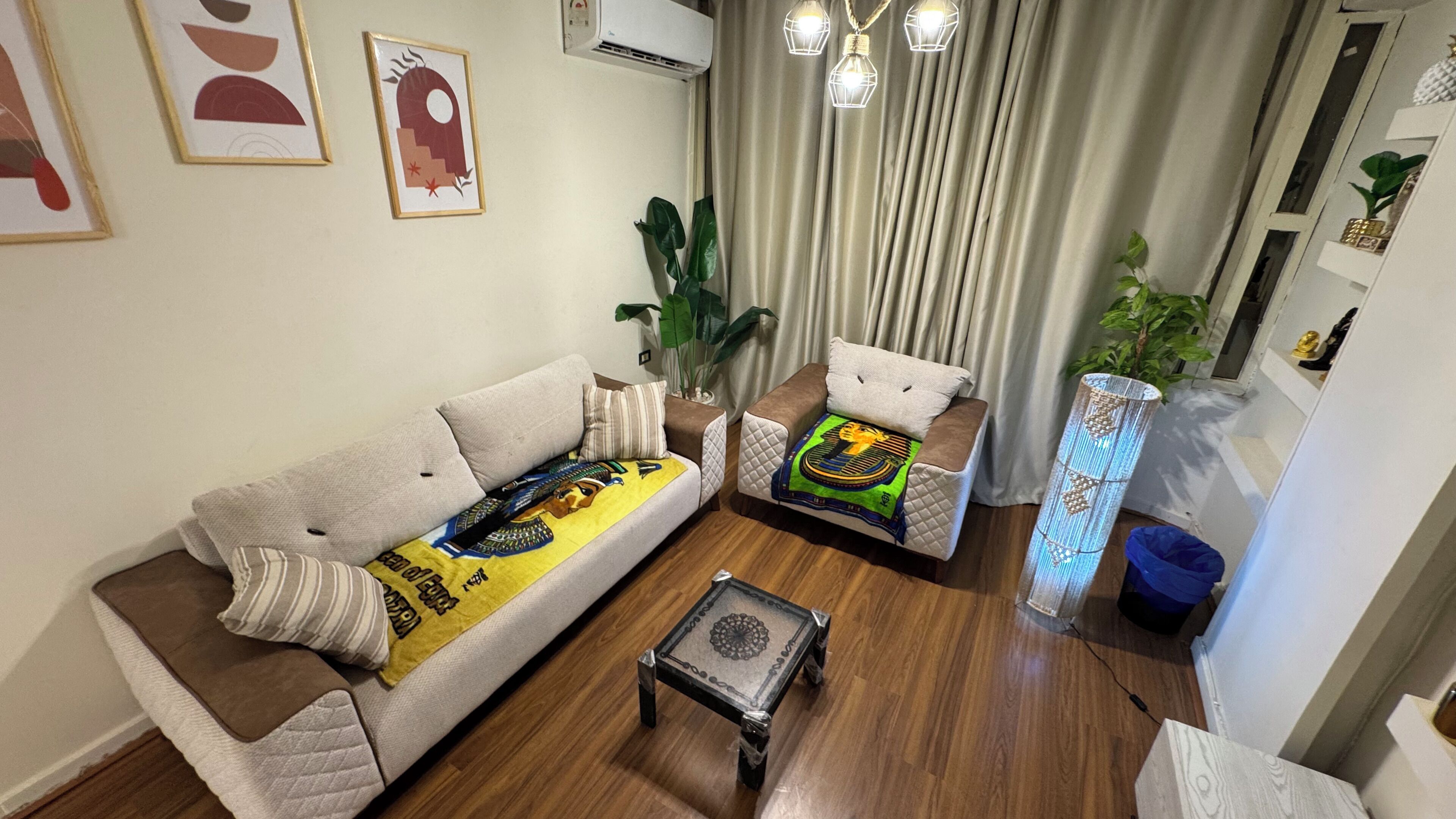 A living room with a sofa, two armchairs, a coffee table, and a potted plant.