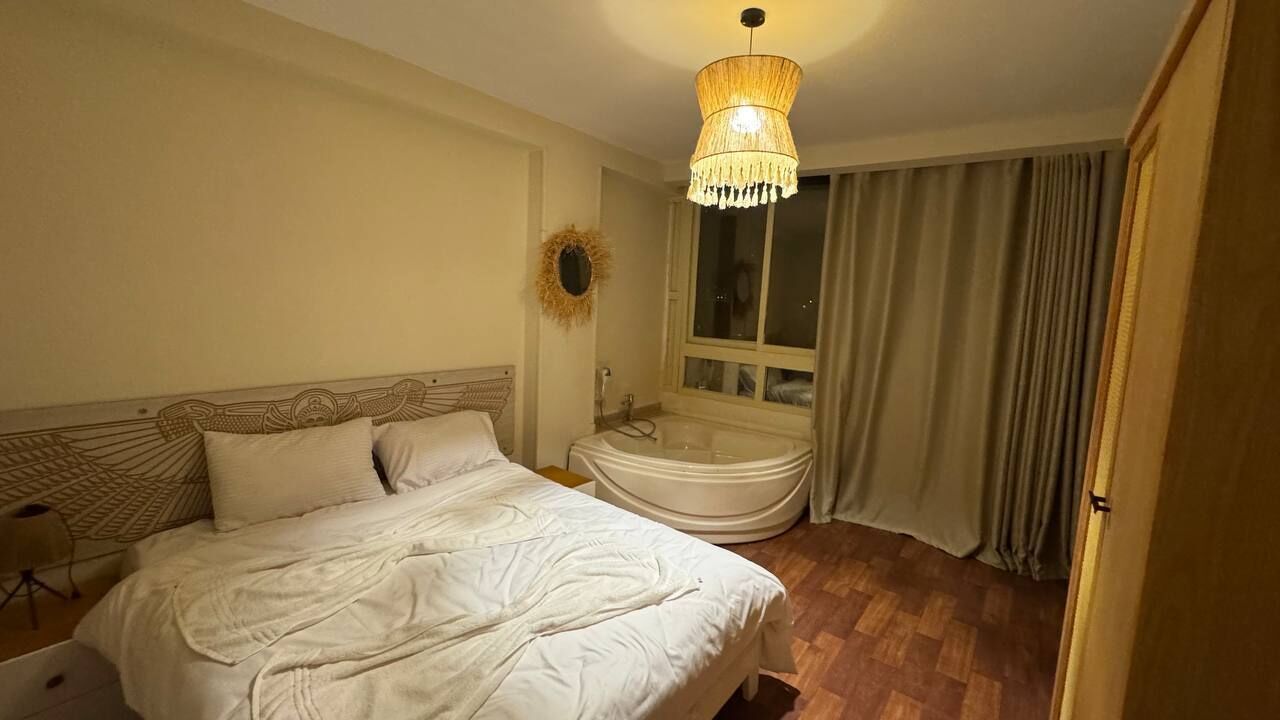 A bedroom with a bed, a vanity with a mirror, and a window with curtains.