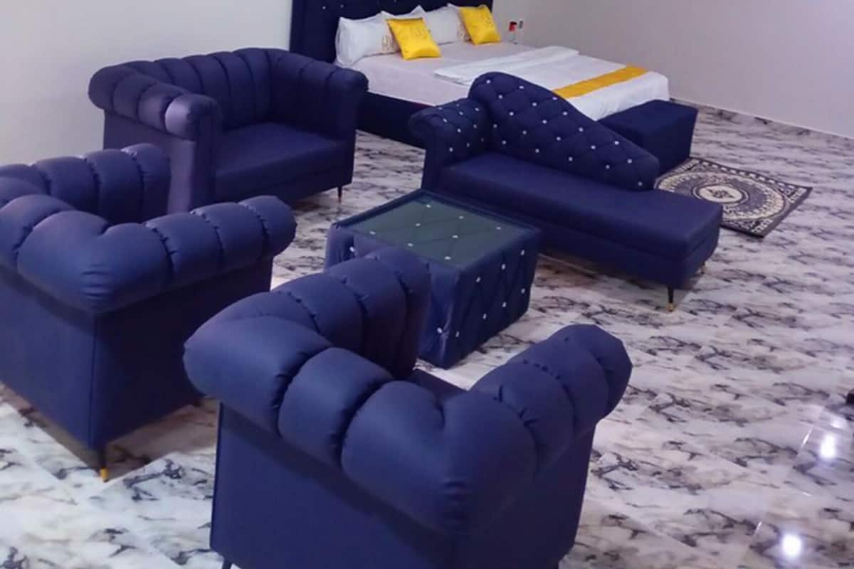 A hotel room with a bed, two armchairs, a sofa, and a coffee table.
