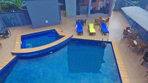 A swimming pool with two sections, surrounded by lounge chairs and tables. - Joddag Hotel and Suites (Eket)