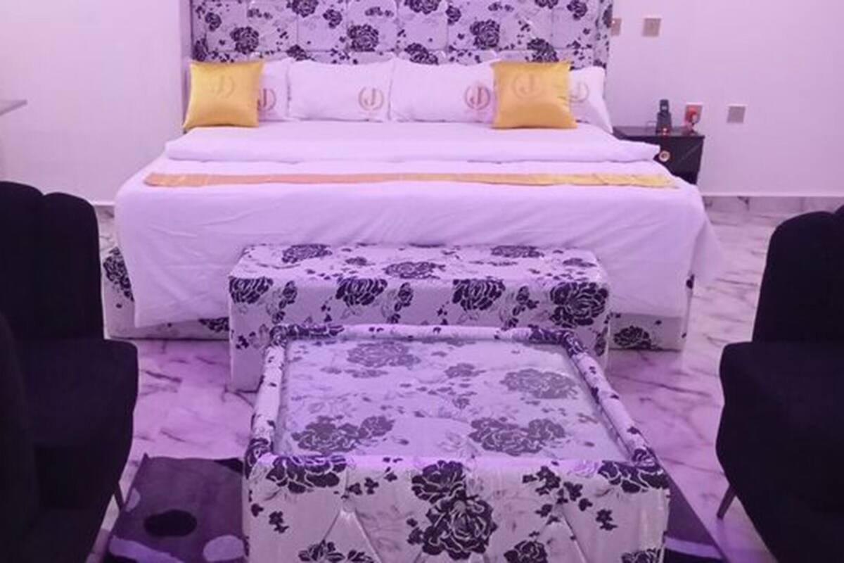 A bedroom with a bed, a bedside table, a chair, and a small table.