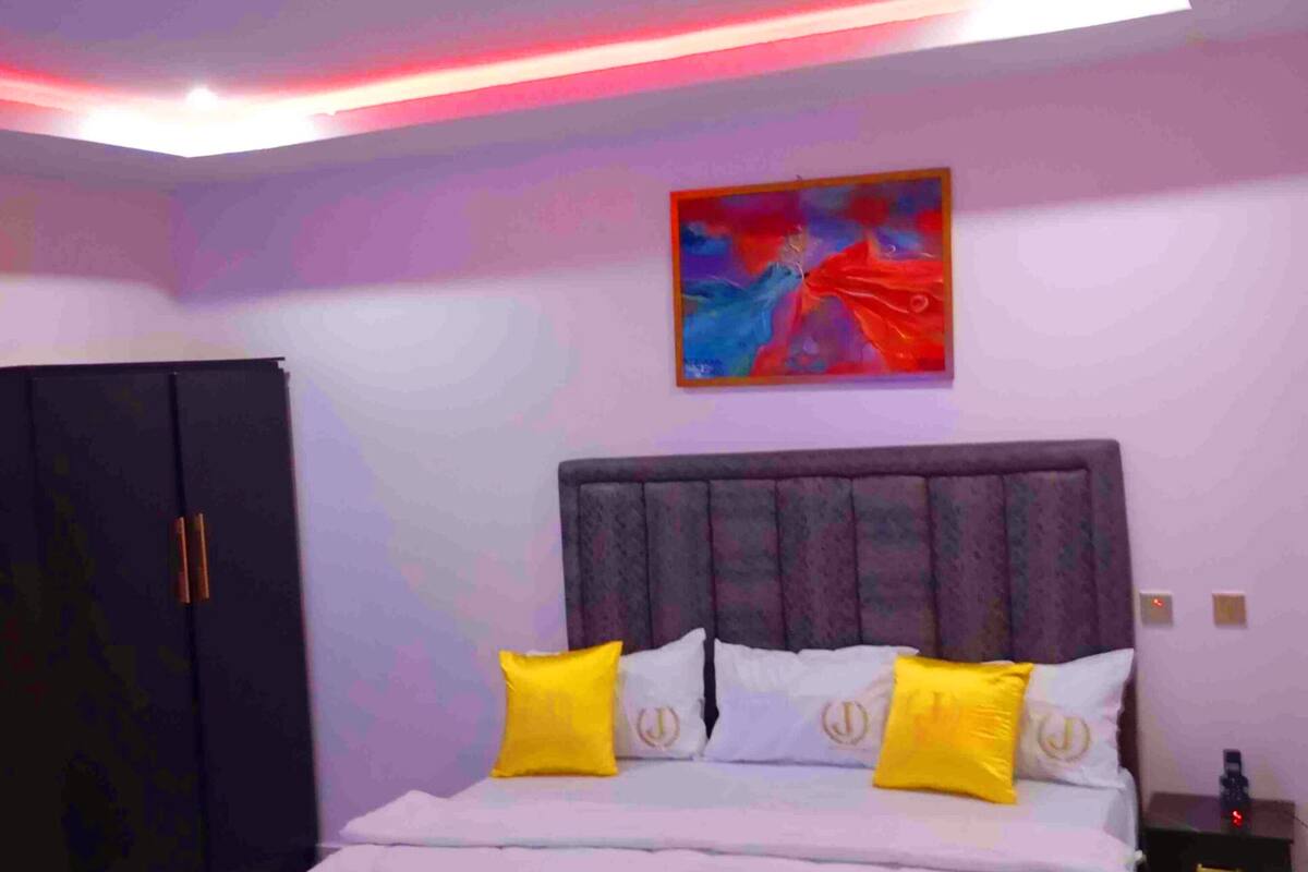 A bedroom with a bed, a nightstand, a wardrobe, and a painting on the wall.