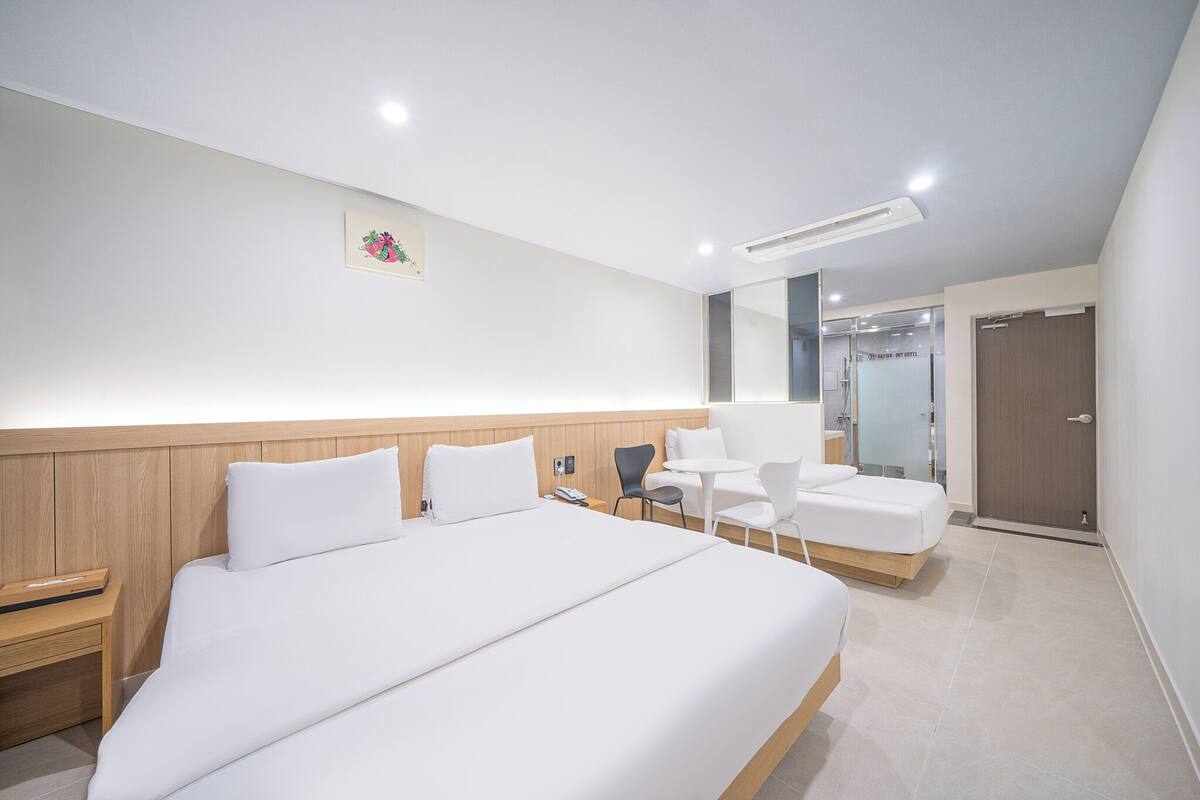 Una habitación de hotel moderna con una cama grande, un escritorio pequeño, una silla y una mesa.