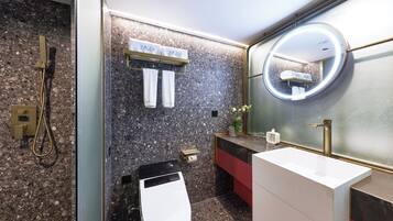 A modern bathroom with a rectangular sink, a toilet, a shower, and a large mirror with a round frame.