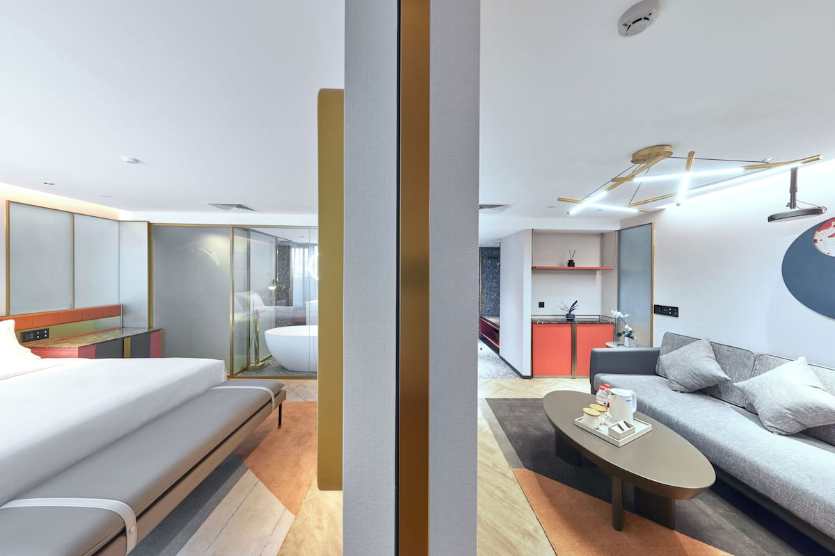 Une chambre d’hôtel moderne équipée d’un lit, d’un canapé, d’une table basse et d’une kitchenette.