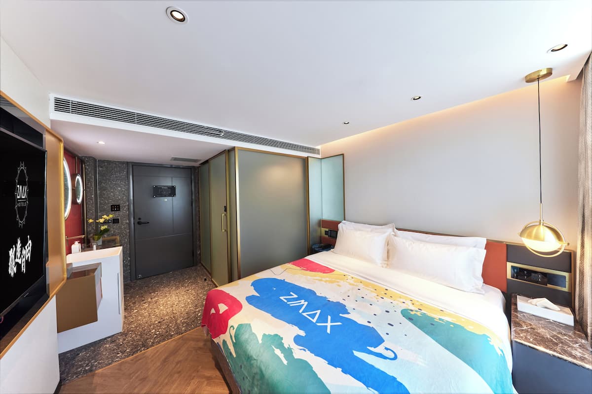 Une chambre d’hôtel comprenant un lit, une coiffeuse avec un miroir, un bureau et une armoire.